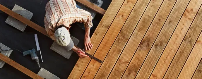 Contractor measuring fresh wood decking boards