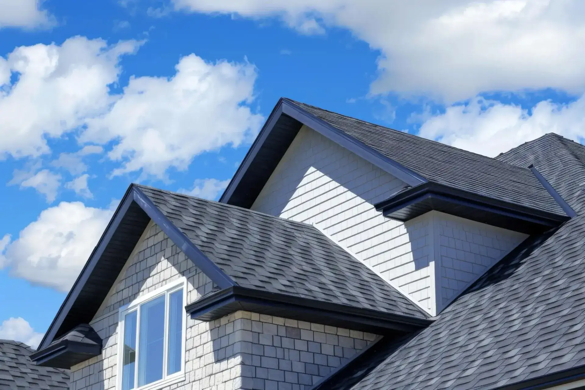Close-up of a home's new dark asphalt shingle roof against a blue sky